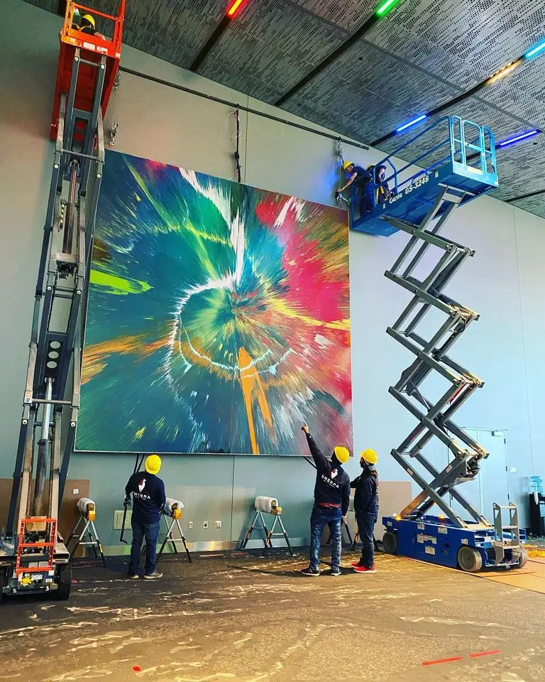 men with hardhats on lifts hanging large artwork in Oklahoma City