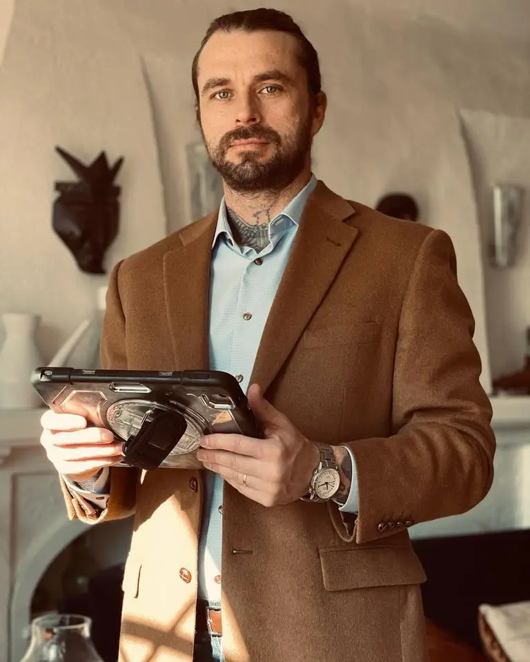 man in brown sport jacket holding tablet